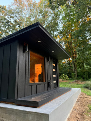 Blackwood outdoor sauna with a glowing window among trees