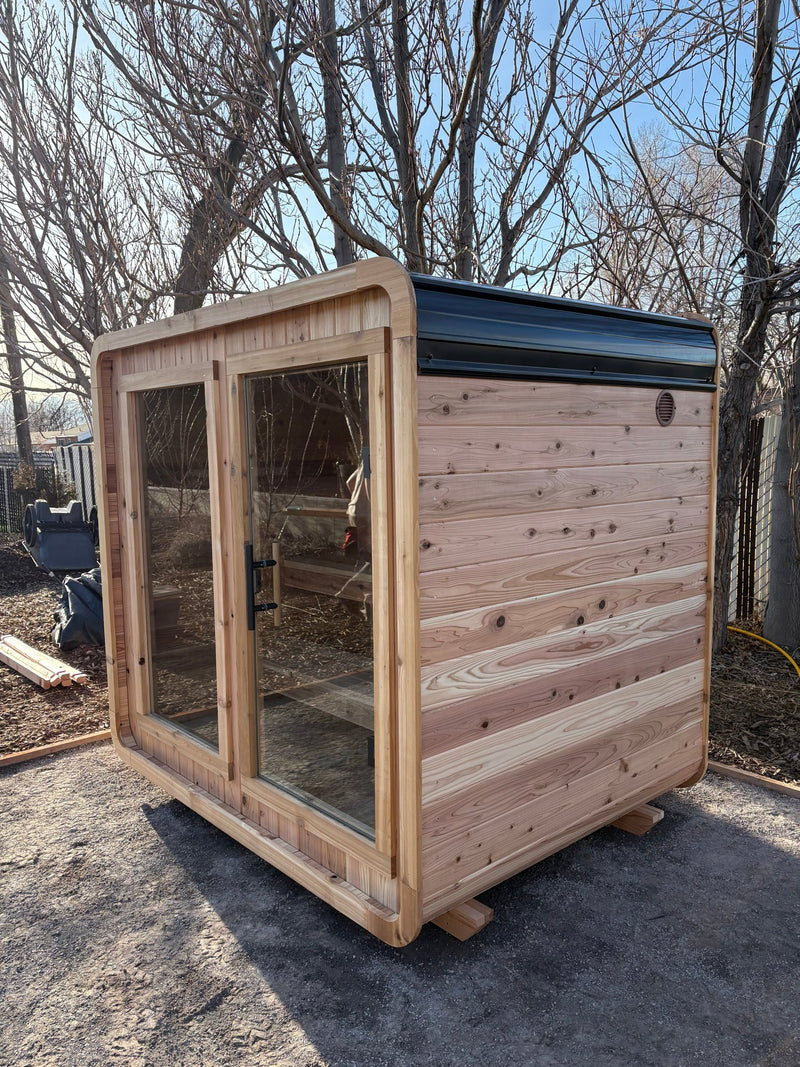 Blazin Cube Sugi cedar outdoor sauna just installed on a gravel backyard pad
