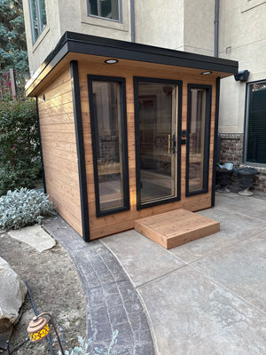 Timberline Lux corner view with cedar siding and glass front by a garden bed